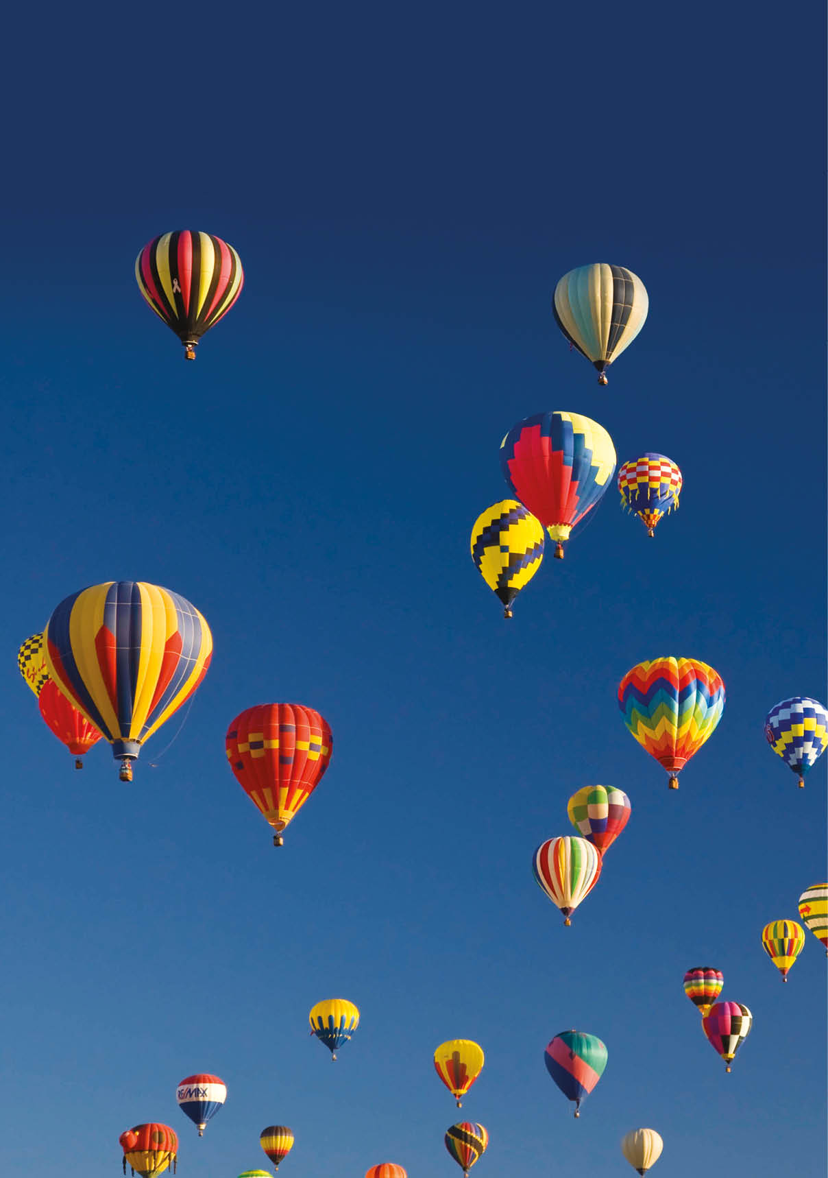 Many vividly colored hot air balloons float in the sky 